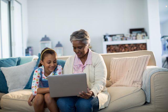 Grandmother and granddaughter using laptop in living room - Download Free Stock Photos Pikwizard.com