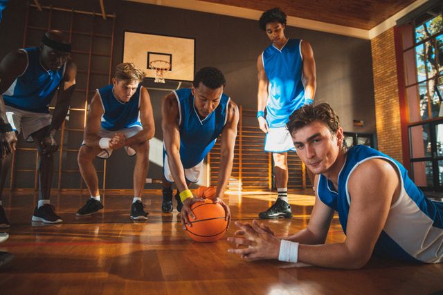 Diverse male basketball team watching and exercising in sunny indoor gym - Download Free Stock Photos Pikwizard.com