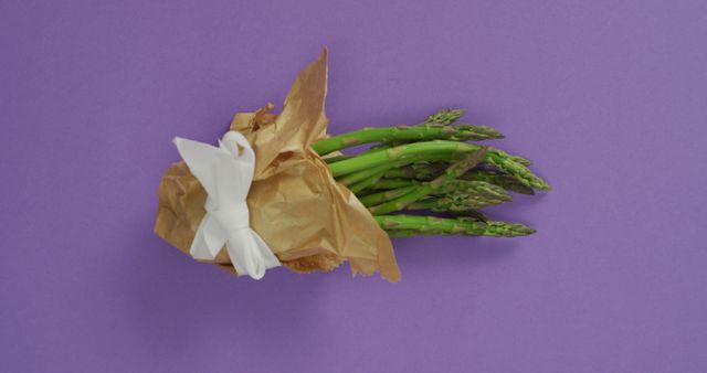 Image of fresh asparagus wrapped with white ribbon and copy space over lilac background. fusion food, fresh vegetables and healthy eating concept.