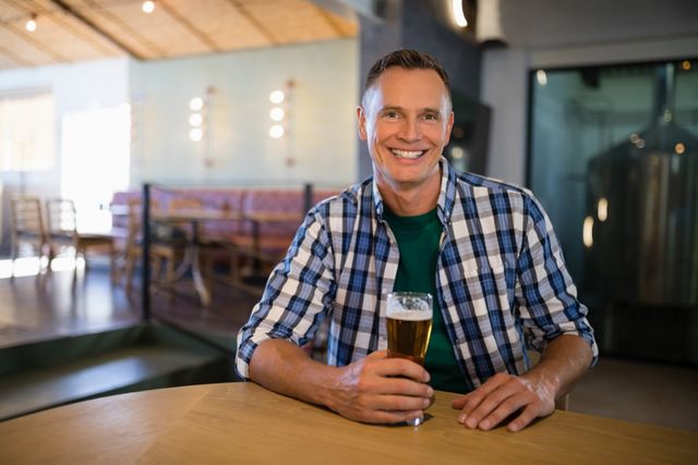 Portrait of smiling man having glass of beer at counter - Download Free Stock Photos Pikwizard.com