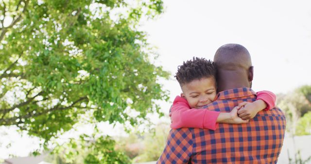 Happy african american father and his son embracing in garden. Spending quality time at home.