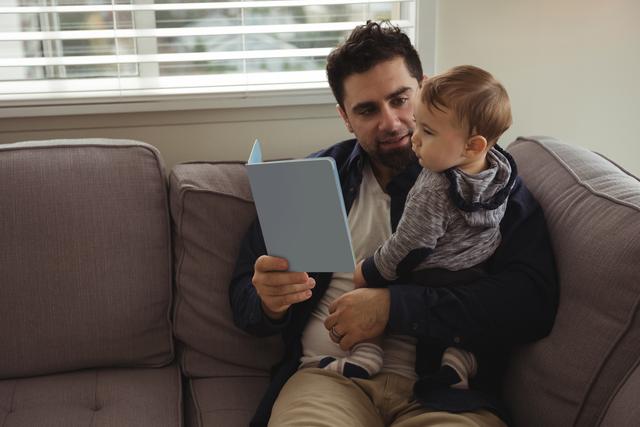 Father reading a book while holding his baby - Download Free Stock Photos Pikwizard.com
