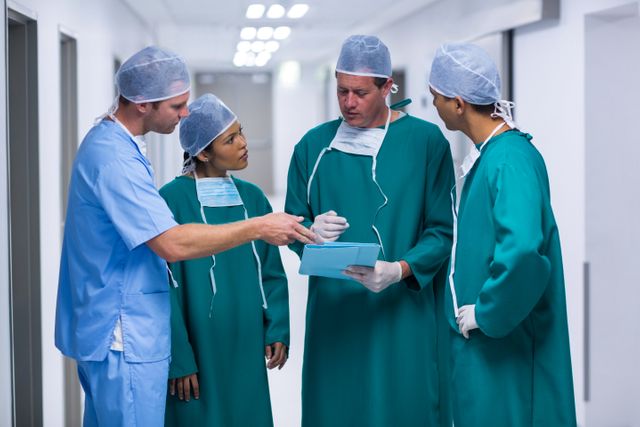 Surgeons and nurse having discussion on file in corridor - Download Free Stock Photos Pikwizard.com