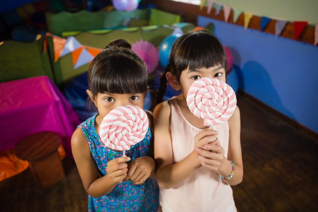 Kids holding a lollipop during birthday party at home - Download Free Stock Photos Pikwizard.com
