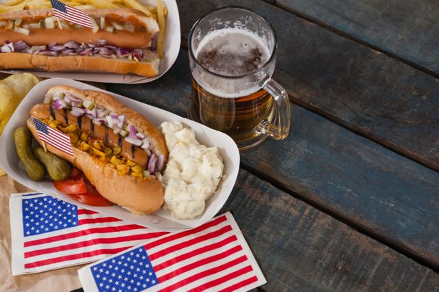 Overhead of hot dog and glass of beer with american flag on wooden table