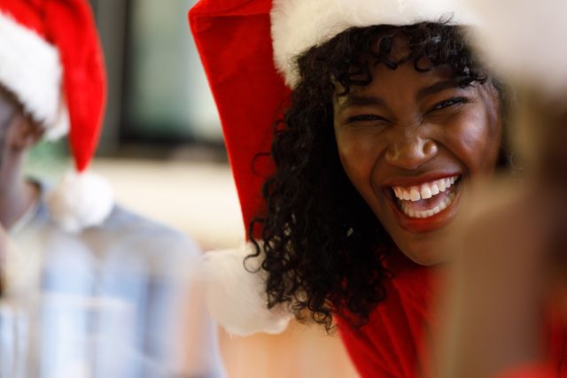 Close up of an african-american woman wearing a santa hat laughing with family at a dinner table - Download Free Stock Photos Pikwizard.com