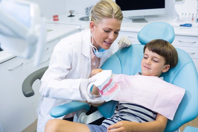 Dentist holding dental mould while talking with boy - Download Free Stock Photos Pikwizard.com