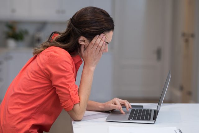 Tensed woman working on laptop at desk