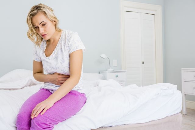 Young woman having stomach pain in bed - Download Free Stock Photos Pikwizard.com