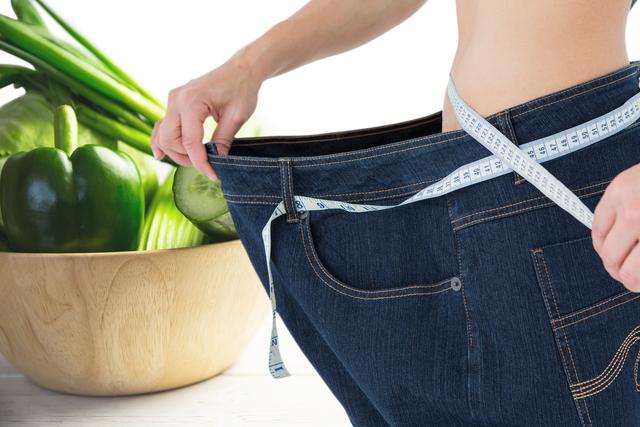Midsection of woman wearing loose jeans with vegetables in background - Download Free Stock Photos Pikwizard.com