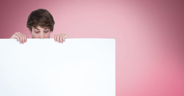 Surprised man looking at blank billboard while standing against pink background - Download Free Stock Photos Pikwizard.com
