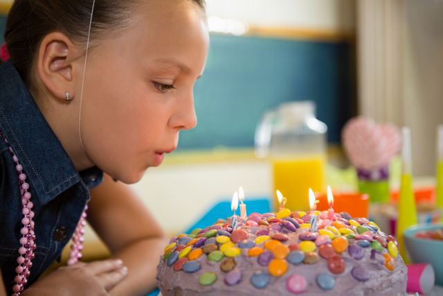 Girl blowing out the candles on a birthday cake - Download Free Stock Photos Pikwizard.com