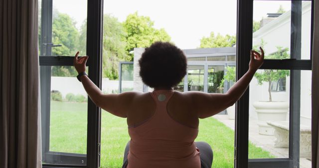 Image of back of plus size african american woman exercising at home, practicing yoga. active healthy lifestyle, exercising at home.