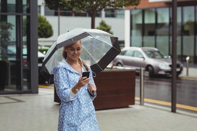 Beautiful woman holding umbrella while using mobile phone - Download Free Stock Photos Pikwizard.com
