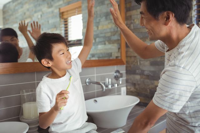 Father and son giving high five to each other in bathroom - Download Free Stock Photos Pikwizard.com