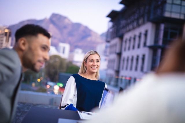Smiling caucasian businesswoman and diverse male colleague in meeting, with mountain and city view. working in business at a modern office.