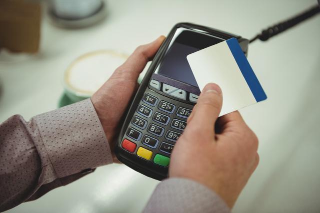 Close-up of hands making payment through credit card in cafe
