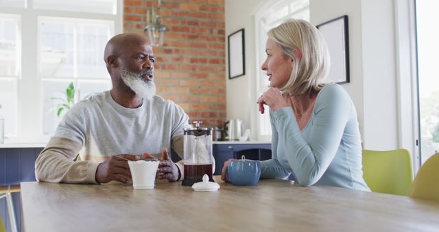 Mixed race senior couple talking to each other while having coffee at home. retirement senior couple lifestyle living concept