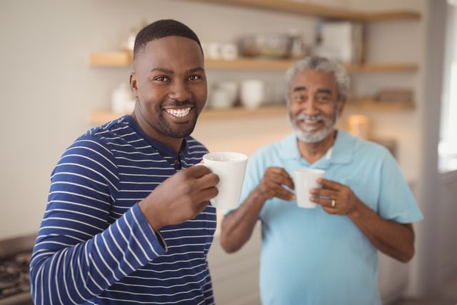 Smiling father and son having cup of coffee in kitchen - Download Free Stock Photos Pikwizard.com