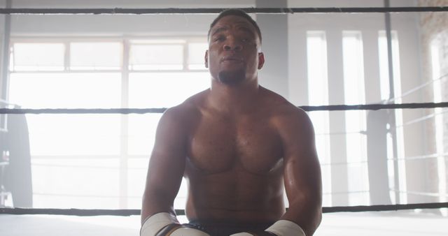 Image of fit and tired african american man after boxing training at gym. active, fit, sporty and healthy lifestyle, exercising at gym concept.