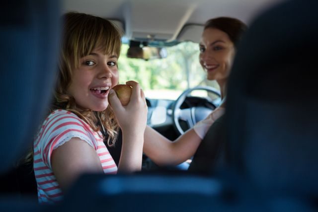 Teenage girl sitting in the back seat while woman driving a car - Download Free Stock Photos Pikwizard.com