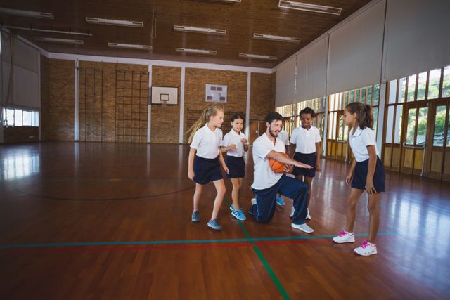 Sports teacher teaching school kids to play basketball - Download Free Stock Photos Pikwizard.com