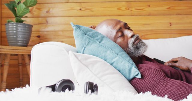 Happy senior african american man spending time in log cabin, sleeping on sofa, slow motion. Free time, domestic life and leisure concept.