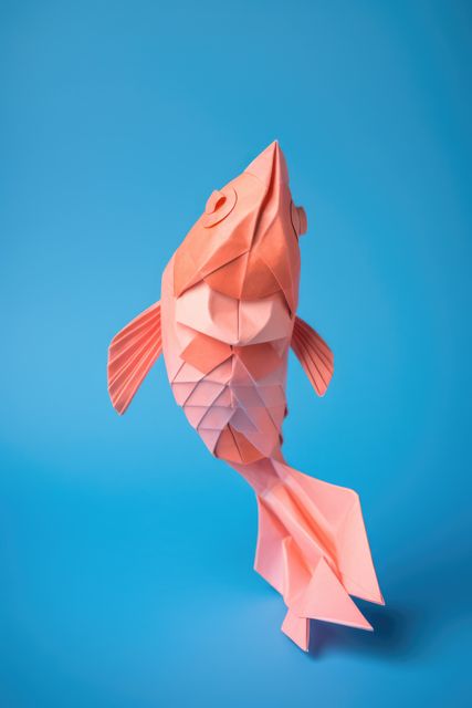 Close up of origami figure of fish on blue background, created using generative ai technology. Origami, art and japanese tradition concept digitally generated image.