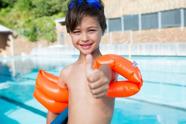 Young boy showing thumbs up at poolside in leisure center