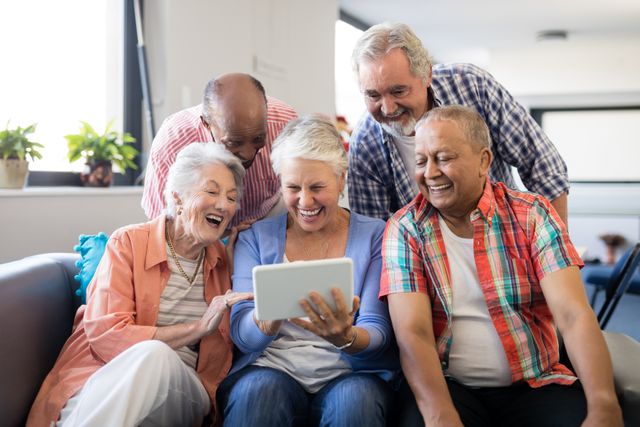 Cheerful senior friends looking at digital tablet - Download Free Stock Photos Pikwizard.com