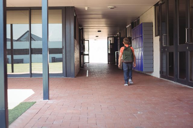 Full length of boy with backpack walking in corridor - Download Free Stock Photos Pikwizard.com