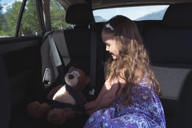 Cute girl tying a teddy bear with seatbelt - Download Free Stock Photos Pikwizard.com