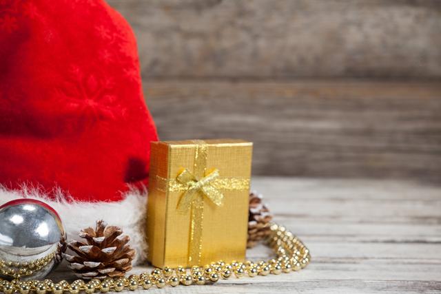 Close-up of Christmas decoration, gift and santa hat kept on wooden table during Christmas time