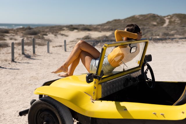 Caucasian woman sitting on beach buggy admiring the view on sunny beach by the sea - Download Free Stock Photos Pikwizard.com