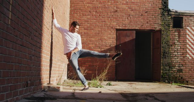 Caucasian male dancer dancing in sunny brick courtyard, copy space - Download Free Stock Photos Pikwizard.com
