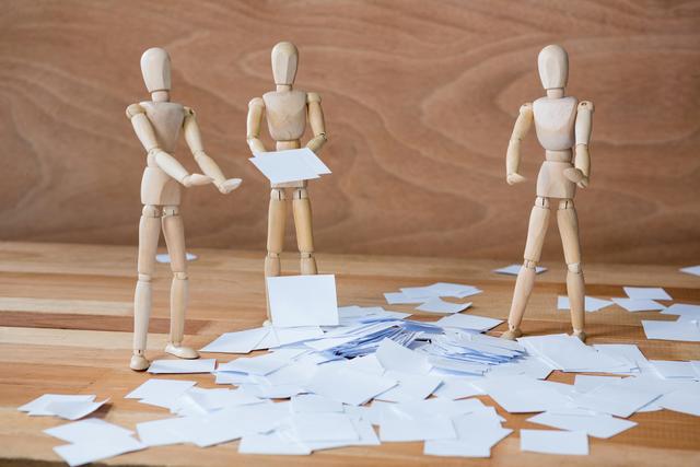 Figurine standing around scattered of paper - Download Free Stock Photos Pikwizard.com