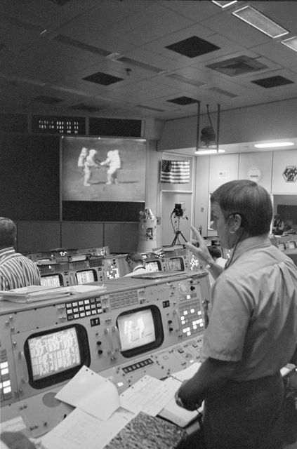 S71-41852 (2 Aug. 1971) --- Gerald D. Griffin, foreground, stands near his console in the Mission Operations Control Room (MOCR) during Apollo 15's third extravehicular activity (EVA) on the lunar surface. Griffin is Gold Team (Shift 1) flight director for the Apollo 15 mission. Astronauts David R. Scott and James B. Irwin can be seen on the large screen at the front of the MOCR as they participate in sample-gathering on the lunar surface.