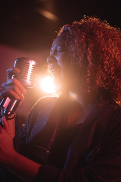 Woman singing on retro microphone in recording studio