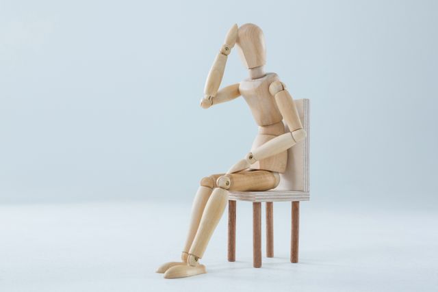 Tired wooden figurine with hand on forehead - Download Free Stock Photos Pikwizard.com