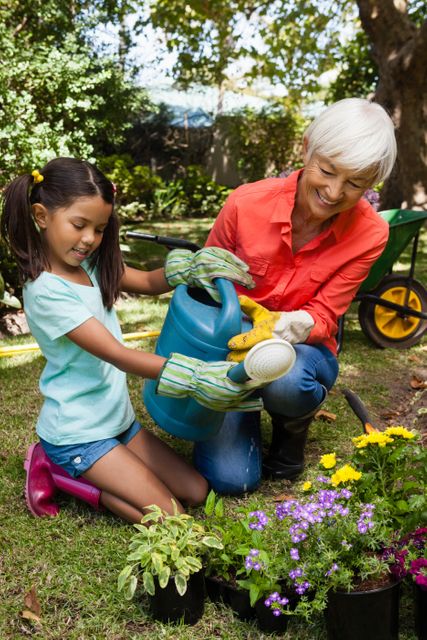 Smiling granddaughter and grandmother watering plants - Download Free Stock Photos Pikwizard.com