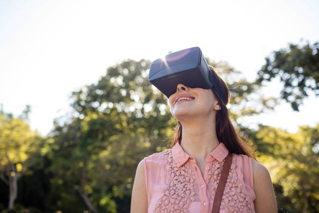 Smiling woman using a VR headset in the park - Download Free Stock Photos Pikwizard.com