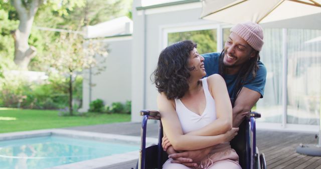 Happy biracial couple embracing in garden, woman in wheelchair, man with dreadlocks. wellbeing and domestic lifestyle with physical disability.