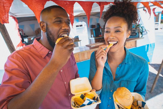 Happy diverse couple enjoying eating takeaway food, standing beside food truck - Download Free Stock Photos Pikwizard.com