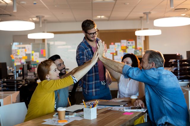 Creative business team giving a high five to each other in office