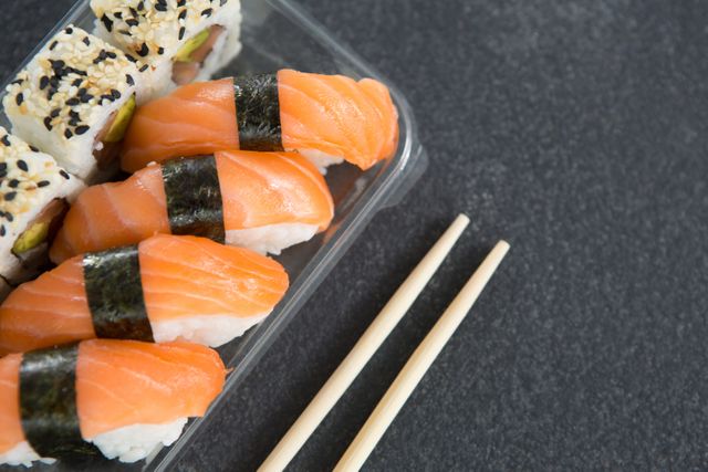 Close-up of sushi rolls with salmon in plastic container