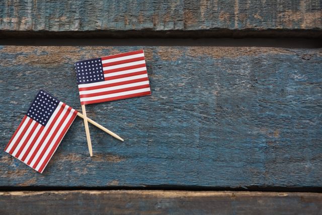 Two crossed American flags on a wooden table