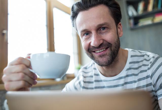 Portrait of smiling man holding a cup of coffee in coffee shop