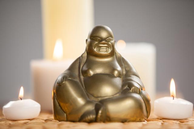 Laughing buddha figurine and lit candles on mat - Download Free Stock Photos Pikwizard.com