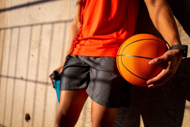 Midsection of fit mixed race man holding basketball - Download Free Stock Photos Pikwizard.com