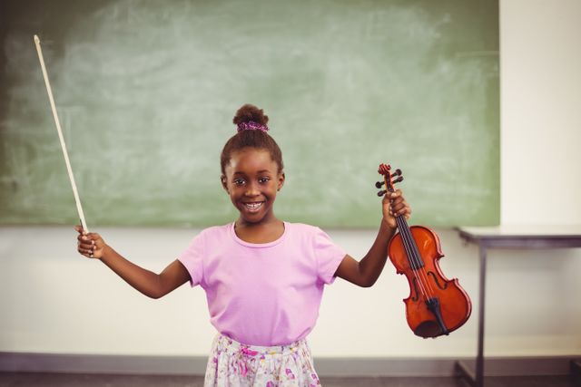 Portrait of smiling schoolgirl holding violin in classroom - Download Free Stock Photos Pikwizard.com